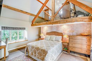 main bedroom with pitched ceiling and exposed beams in barn conversion for sale in Church Minshull