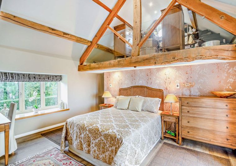 main bedroom with pitched ceiling and exposed beams in barn conversion for sale in Church Minshull
